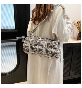 Detail of a minimalist striped knit shoulder bag with a wide woven geometric strap
