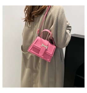 Detail of pink rectangular handbag with gold metal clasp worn over a beige coat