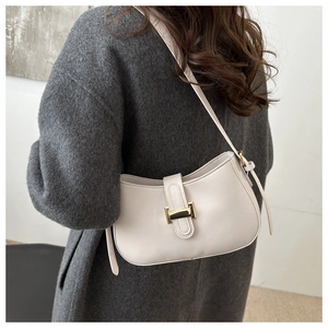 Close-up of minimalist beige half-moon bag with gold buckle on a grey wool coat