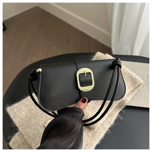 Macro detail of black leather shoulder bag featuring a vintage gold oval metal buckle