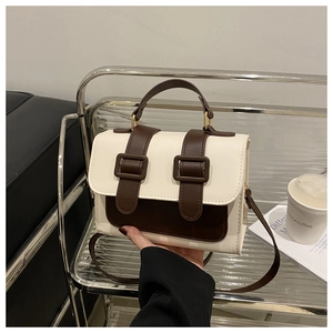 Detail of color-block flap bag in cream and dark brown PU leather with decorative buckles