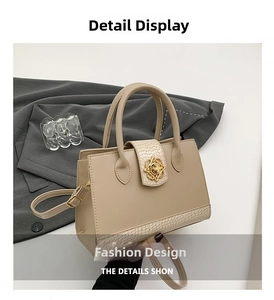 Detail view of beige trapezoid handbag with croc-embossed texture and gold floral buckle