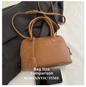 Dettaglio borsa in pelle opaca marrone con cuciture bianche e ciondolo decorativo