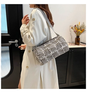 Detail of a black and white striped cylindrical shoulder bag with a wide woven strap
