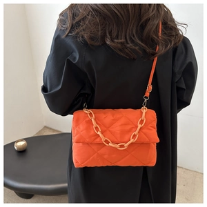 Détail du sac bandoulière matelassé orange avec chaîne épaisse et texture gonflée