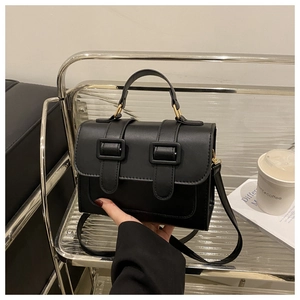 Detail of a chic black flap bag with square buckles on a stylish display stand