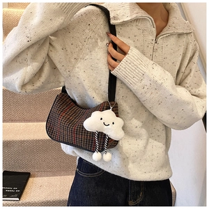 Retro houndstooth underarm bag with a white plush cloud charm shown on a model