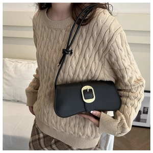Détail d'un sac porté épaule en cuir noir avec fermoir doré et pendentif de cavalier