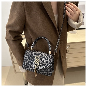 Détail du petit sac carré à motif léopard avec pompon doré et bandoulière amovible