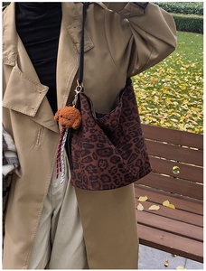 Close-up of leopard print hobo tote bag with teddy bear charm in a street style setting