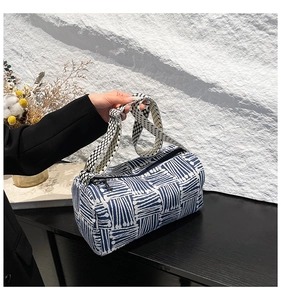 Detail of blue and white geometric pattern handbag with thick woven strap on wood
