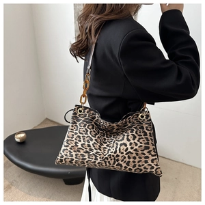 Sac léopard avec chaîne en acrylique ambre porté par un mannequin en costume noir