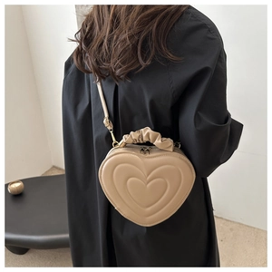 Detail of heart-shaped leather bag with ruched handle and adjustable shoulder strap