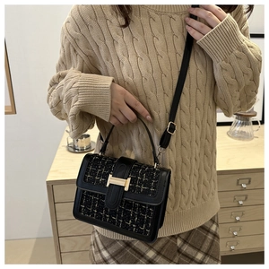 Close-up of black and gold tweed crossbody bag featuring a golden H-shaped buckle