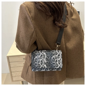Detail der Crossbody-Tasche mit Leopardenmuster und gewebtem Gurt an einem Model