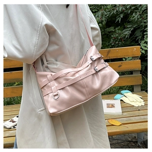 Detail of dusty rose shoulder bag with parallel silver buckles on autumn background