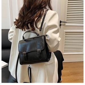 Detail of vintage black leather backpack with double buckles on a model in white blazer