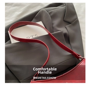 Détail de la poignée du sac en cuir rouge avec boucles métalliques argentées et coutures