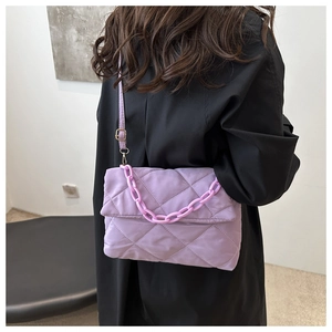 Sac bandoulière matelassé violet avec grosse chaîne en acrylique porté par un modèle