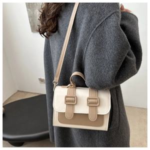Detail of a contrast color crossbody bag styled with a dark wool coat in a modern setting