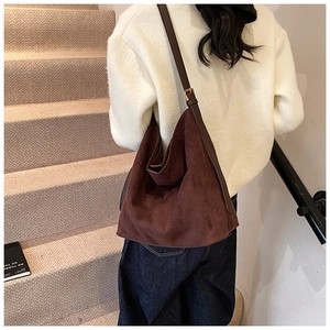 Detail of a large brown suede tote bag featuring adjustable leather shoulder straps