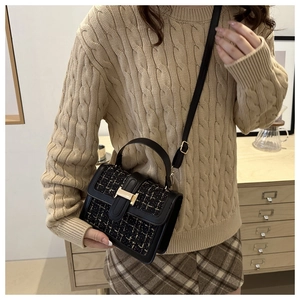 Chic black tweed crossbody bag with gold hardware details on elegant model outfit