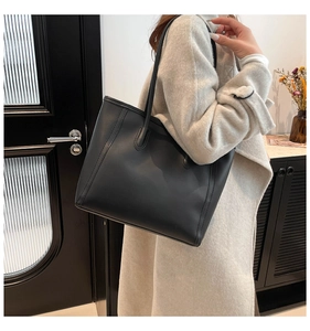 Detailed view of black matte leather tote bag with vertical stitching on minimalist shoulder bag