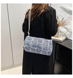Detail of blue and white striped cylindrical bag with checkered strap on model