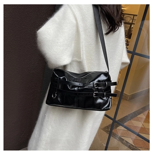 Detail of black glossy shoulder bag with silver belt buckle on white fur coat