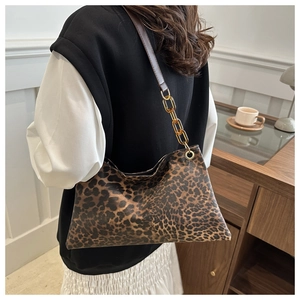 Détail d'un sac léopard avec bandoulière en chaîne de résine et lanière en cuir marron