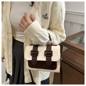 Detail of a retro two-tone contrast small square bag with decorative brown straps