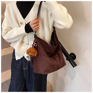 Detail of dark brown suede tote bag featuring a cute teddy bear charm and printed scarf