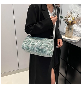 Detail of green striped pillow bag with geometric wide strap shown on shoulder