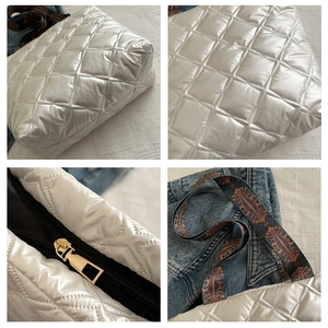 Detail of silver quilted tote bag featuring golden zipper and patterned strap on denim