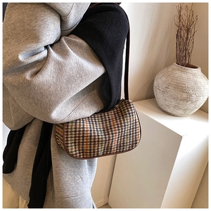 Detail of vintage multicolored plaid woven underarm bag with premium brown leather piping
