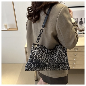 Detailed side view of leopard print canvas tote bag with black leather shoulder strap
