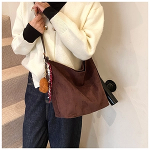 Detail of suede-textured dark brown tote bag featuring a cute plush bear charm and scarf