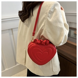 Detail of red heart-shaped shoulder bag with ruffled edges and gold hardware