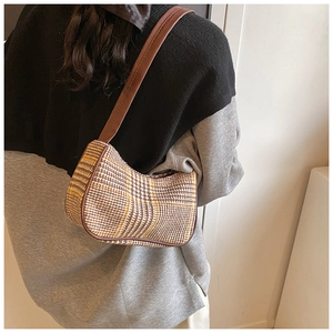 Close-up of retro plaid underarm bag with brown leather trim and tweed fabric texture