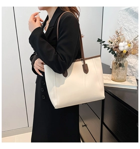 Detail of cream leather tote bag with brown straps shown on shoulder for daily use