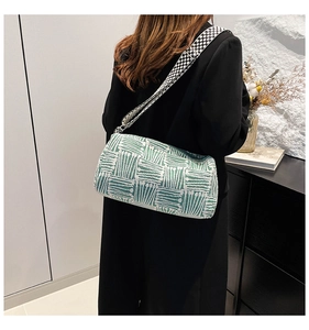 Detailed side view of green striped knitted cylinder bag with polka dot wide strap
