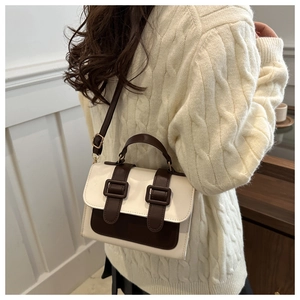 Detail of retro color-block messenger bag styled with a white cable-knit sweater