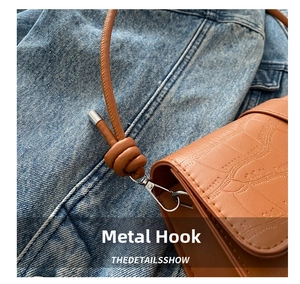 Detail of brown croc-embossed bag featuring silver hardware hooks and knotted shoulder strap