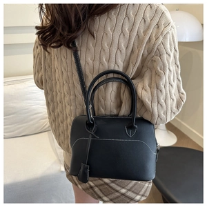 Dettaglio di una borsa in pelle nera opaca con cuciture a contrasto bianche e manici