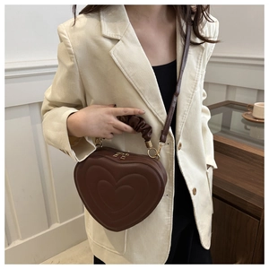 Detailed view of a brown heart-shaped crossbody bag with quilted stitching and gold hardware
