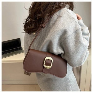 Detail of a brown retro baguette bag with a gold buckle and knotted shoulder strap