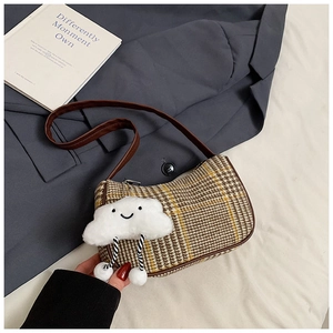 Close-up of checkered plaid wool shoulder bag with a cute plush cloud charm