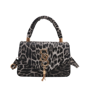 Sac léopard élégant avec logo S doré et gland décoratif sur fond blanc immaculé
