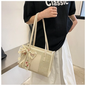 Detail of straw woven bag with floral lace bow and leather patch on off-white texture
