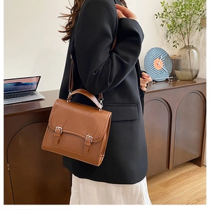 Close-up of vintage brown messenger bag with double buckles on a lifestyle background